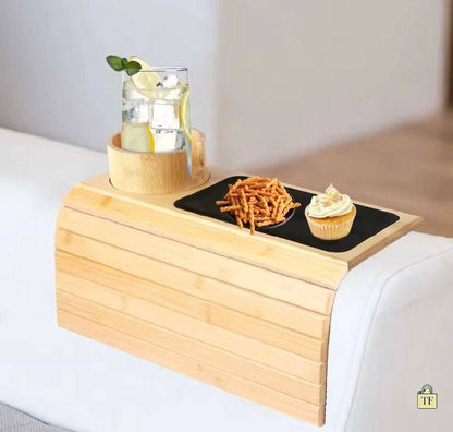 Wooden tray on a bed with a glass of water, snacks, and a cupcake.
