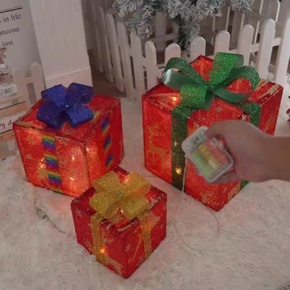 Decorative red gift boxes with colorful bows on a white surface, with a hand holding a small battery box